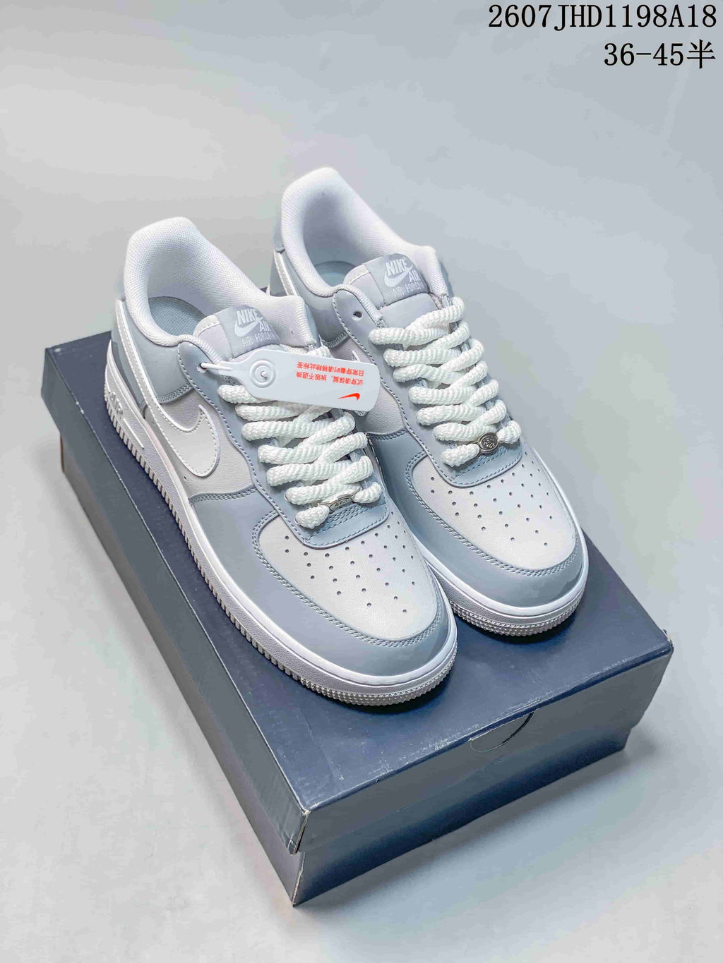 Gray and white Nike Air Force 1 ’07 low-top sneakers displayed on a shoebox, with the source size note visible above.