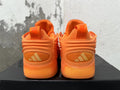 Rear view of orange Adidas basketball sneakers showing heel panels, pull tabs, and branding.