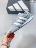 Side profile of the gray low-top sneaker with three white stripes and a white midsole.