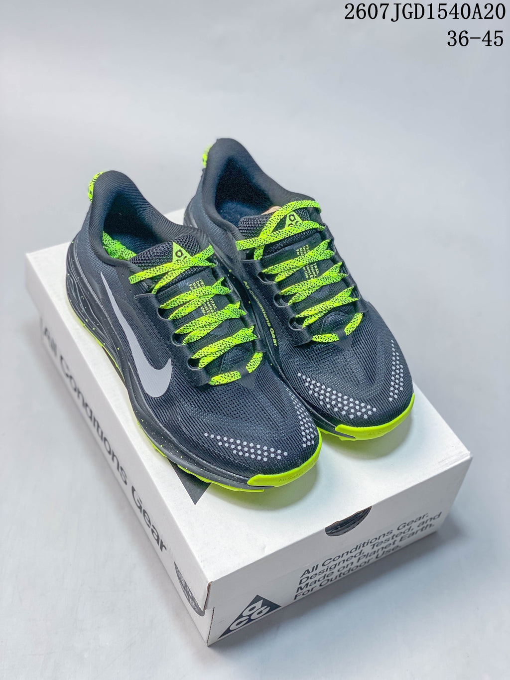 Pair of dark gray and neon green Nike ACG Pegasus Trail sneakers displayed on a shoebox.