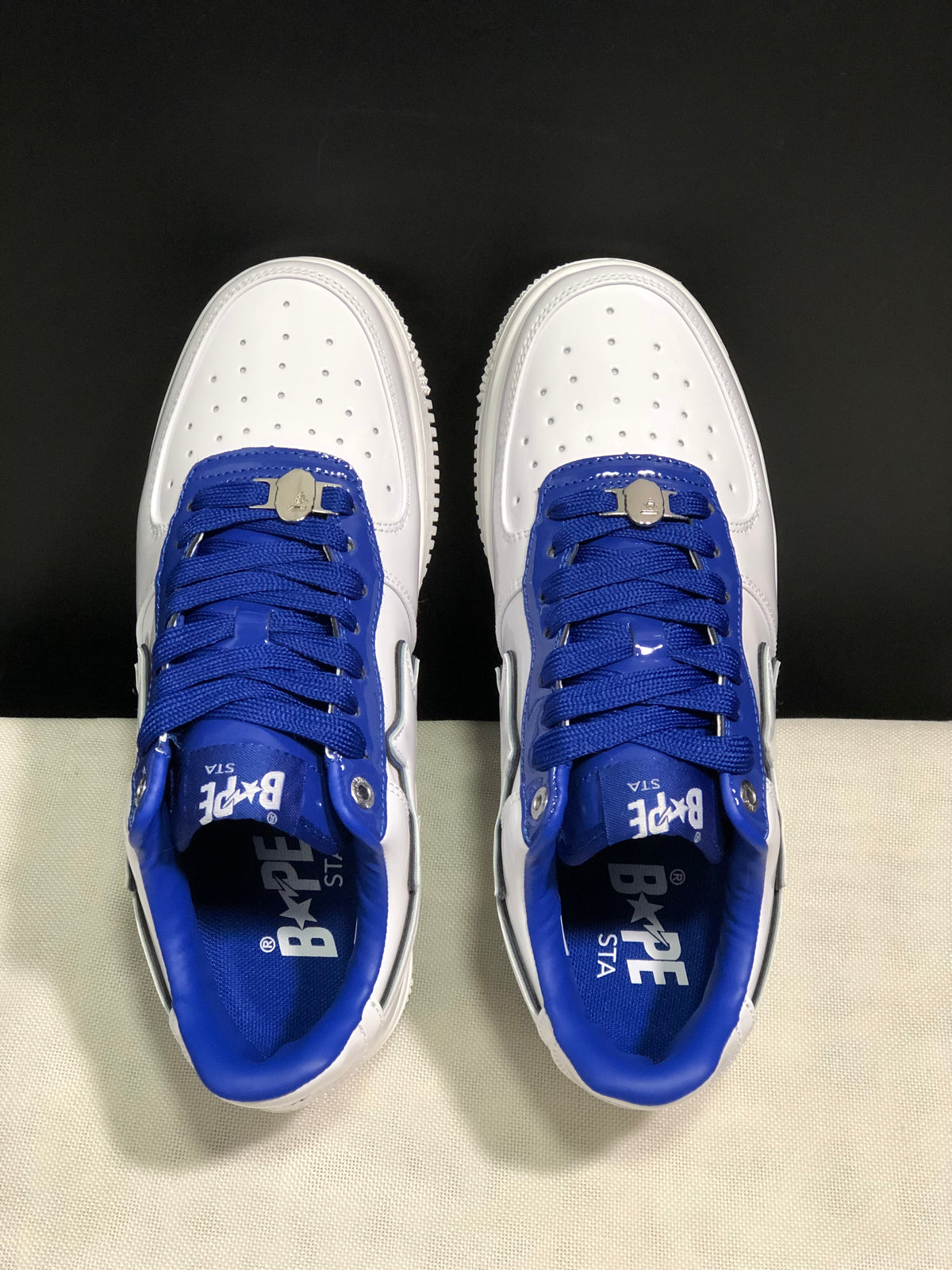 Top view showing the perforated white toe boxes, blue laces, blue tongue panels, and metal lace details.