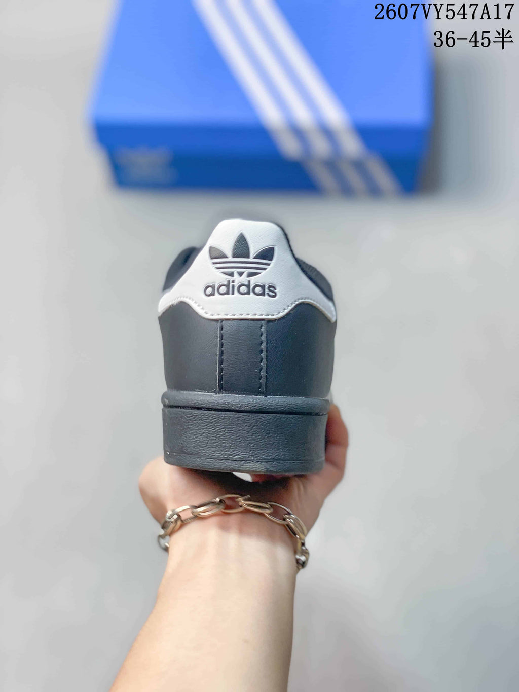 Rear view of a black Adidas Superstar sneaker showing the white heel tab and Adidas logo.
