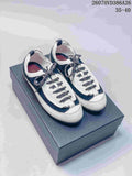 Pair of black-and-white Chanel low-top sneakers displayed on a box, with patterned laces and rounded toes.