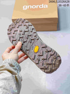 Underside of an olive hiking shoe showing a deeply patterned tread; box in the background.