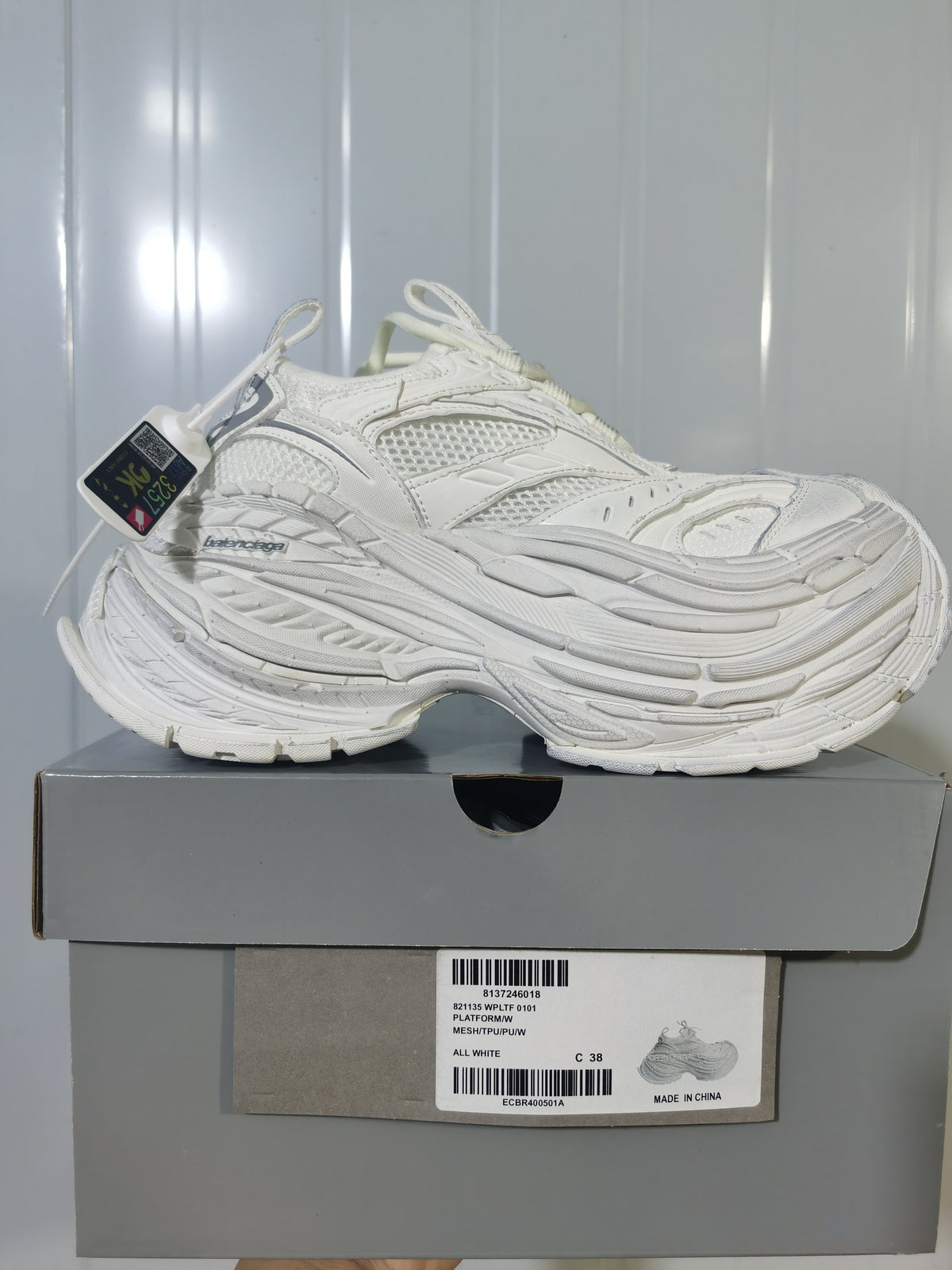 Side profile of the all-white sneaker resting on its box; the box label shows PLATFORM/MW, ALL WHITE, and sample size C 38.