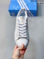 Top view of the white lace-up sneaker with Stan Smith tongue branding and a portrait graphic.