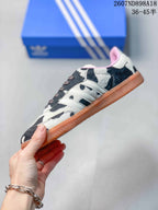 Side profile showing the cow-print upper, white three stripes, lace-up construction and gum-colored outsole.