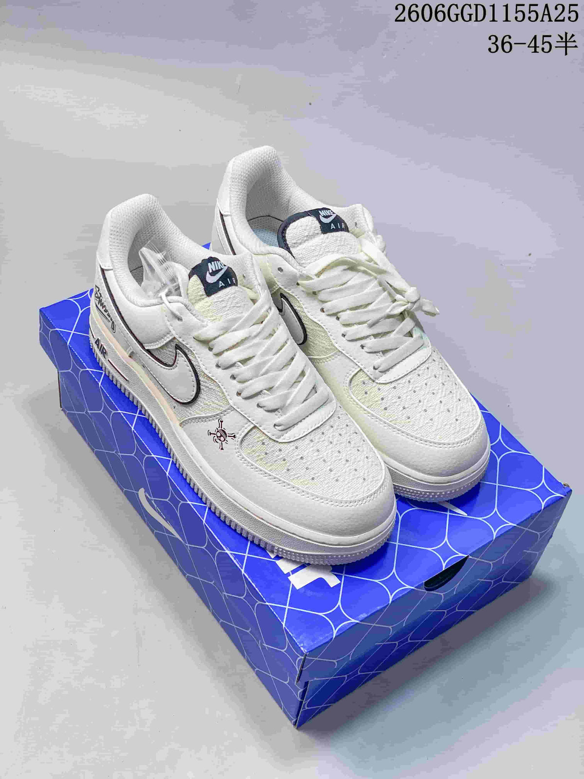 Pair of off-white Nike Air Force 1-style sneakers with skull graphics and a dark-outlined Swoosh, shown on a blue shoebox.