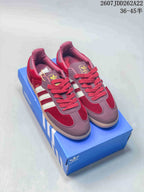 Pair of burgundy and white adidas Samba sneakers displayed on a blue shoebox.