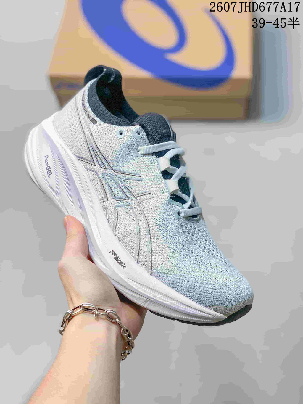Light gray and white ASICS Gel-Nimbus 26 sneaker with reflective-looking side details, dark collar lining, and a sculpted white midsole.