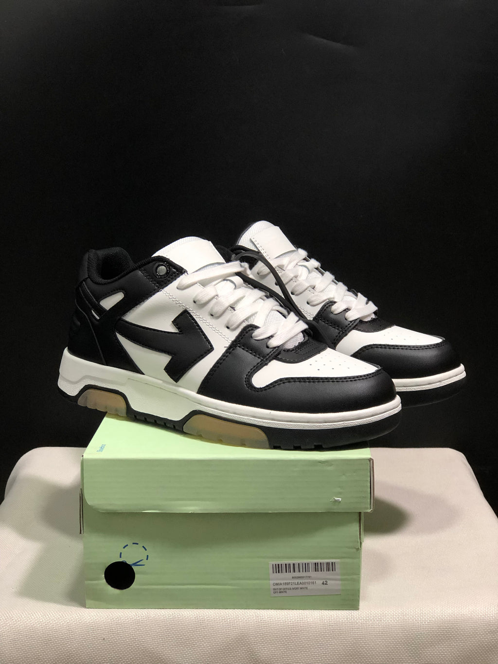 Black and white Off-White Out Of Office sneakers displayed with a green shoebox; the box label shows size 42.