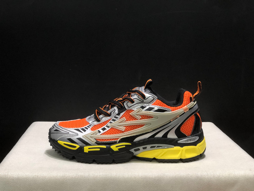 Outer side profile showing the arrow-shaped overlays, orange upper panels, black accents, and yellow midsole area.