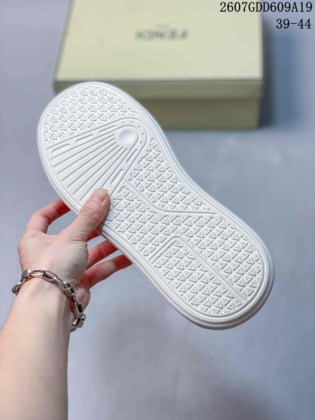 White outsole of the sneaker showing a repeating geometric tread pattern and linear grooves.