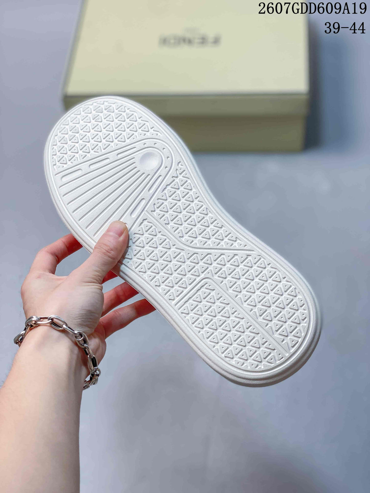 White outsole of the sneaker showing a repeating geometric tread pattern and linear grooves.