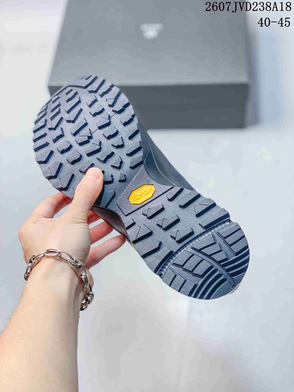 Underside view of a dark gray hiking shoe showing a deep lugged outsole and visible Vibram mark.