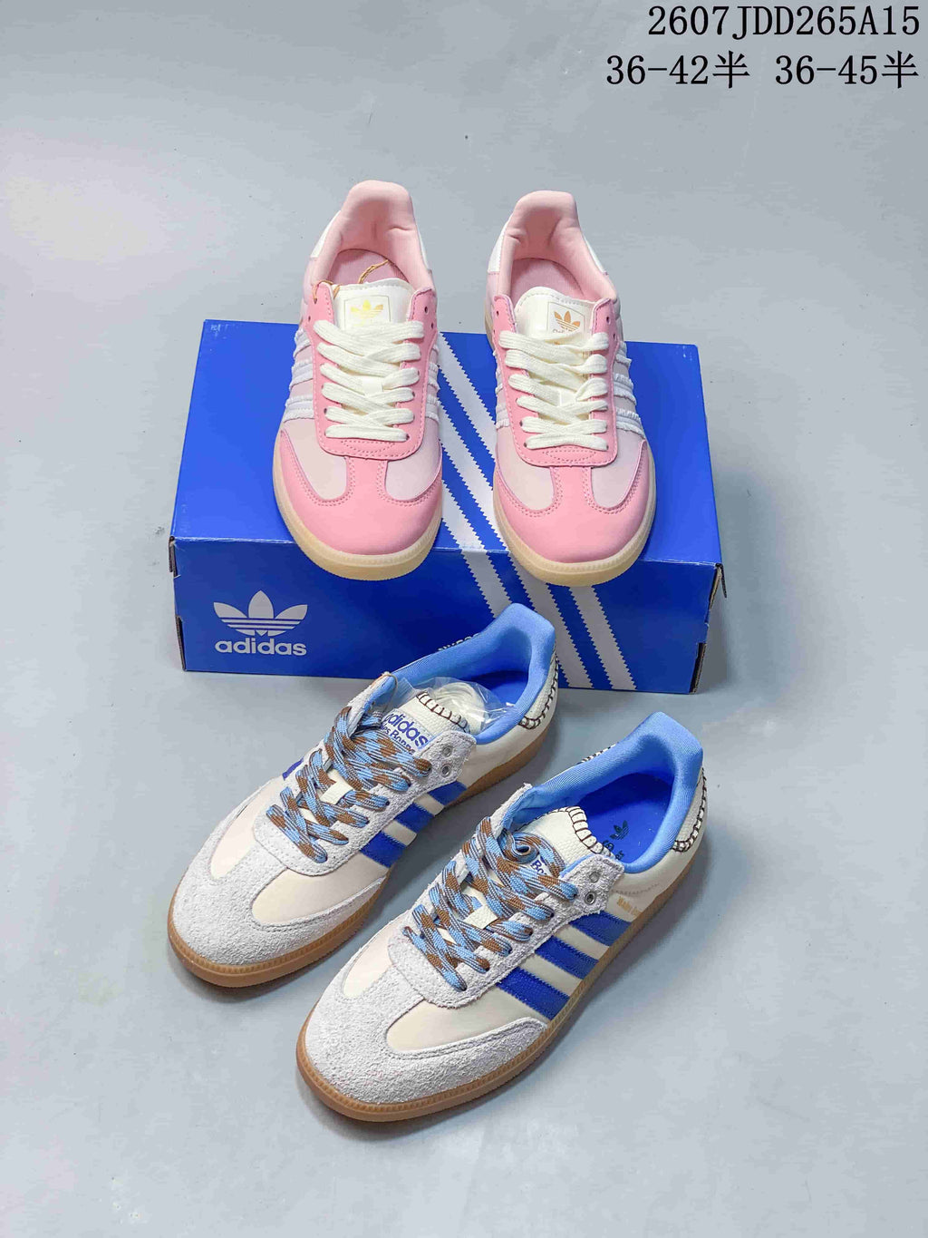Both pictured adidas Samba colorways arranged together: pink and white sneakers on a blue box and white and blue sneakers in the foreground.