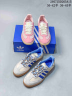 Both pictured adidas Samba colorways arranged together: pink and white sneakers on a blue box and white and blue sneakers in the foreground.