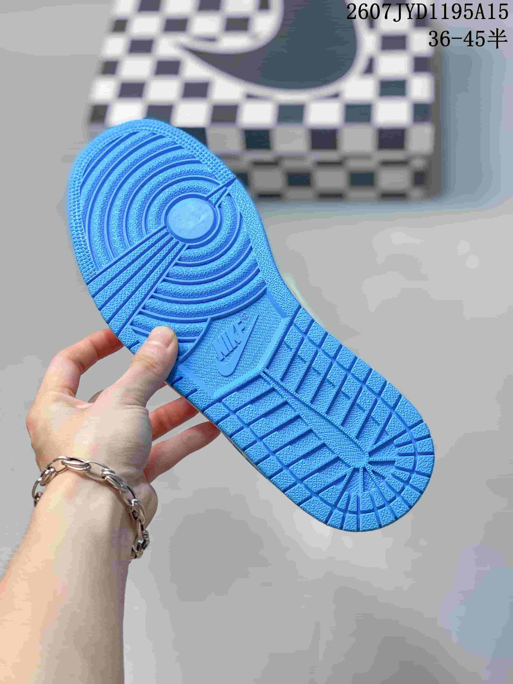 Blue rubber outsole held in hand, showing circular traction rings and patterned tread.