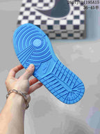 Blue rubber outsole held in hand, showing circular traction rings and patterned tread.