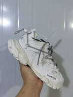 Close-up view of a white Balenciaga Track Trail sneaker showing the layered upper, rope-style laces, and chunky sole.