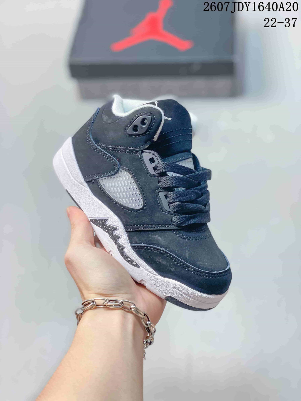 Black kids' mid-top sneaker with white outsole accents, dark laces, and contrasting side panels.