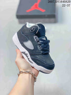 Black kids' mid-top sneaker with white outsole accents, dark laces, and contrasting side panels.