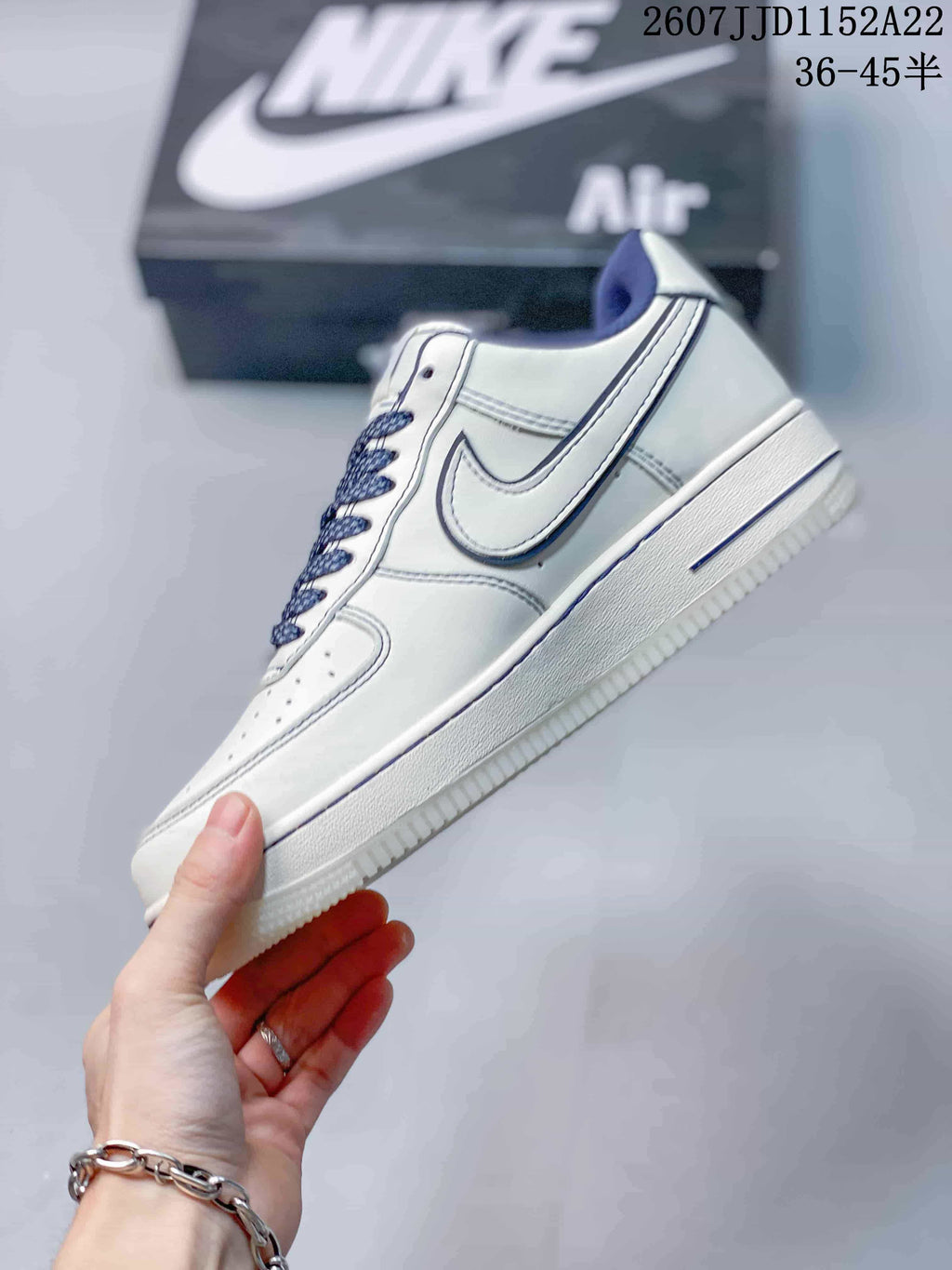Side profile of the white low-top sneaker showing the blue-outlined Swoosh, layered panels and textured white outsole.