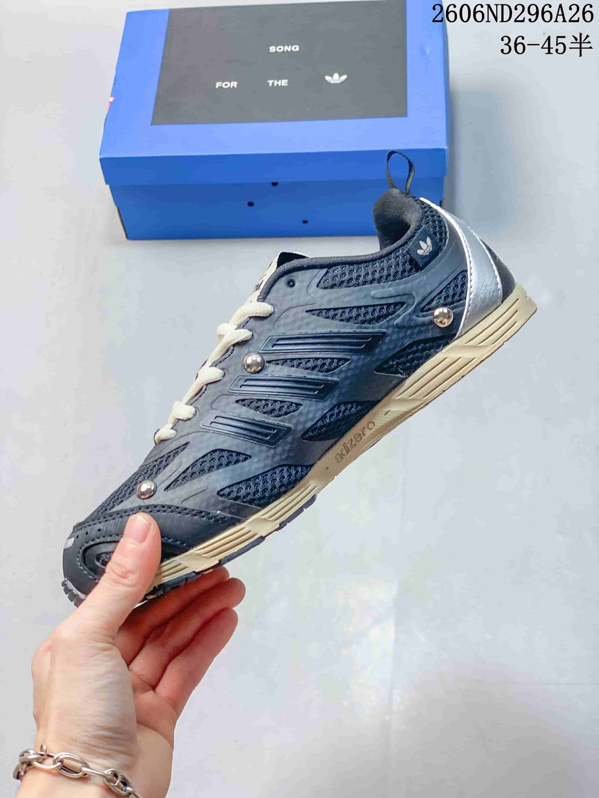 Side view showing layered panels, mesh-textured sections, cream outsole details, and metallic studs.