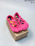 Pink Vibram five-toe training shoes displayed on a shoebox, showing the strapped upper and individual toe compartments.