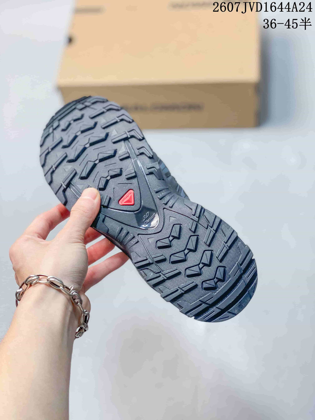 Close view of the Salomon sneaker outsole showing a deep lugged tread pattern and red triangular detail.