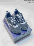 Pair of dark gray and black Dior low-top sneakers with silver-gray accents displayed on a shoebox.