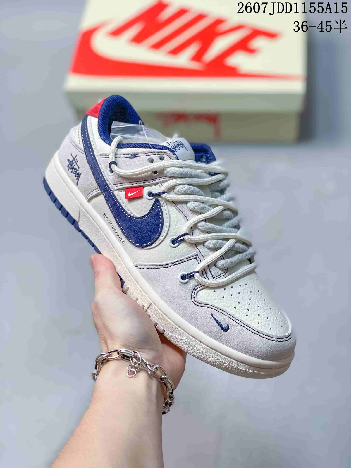 Side view of a white and navy low-top sneaker showing the contrast Swoosh, red side label and textured outsole.