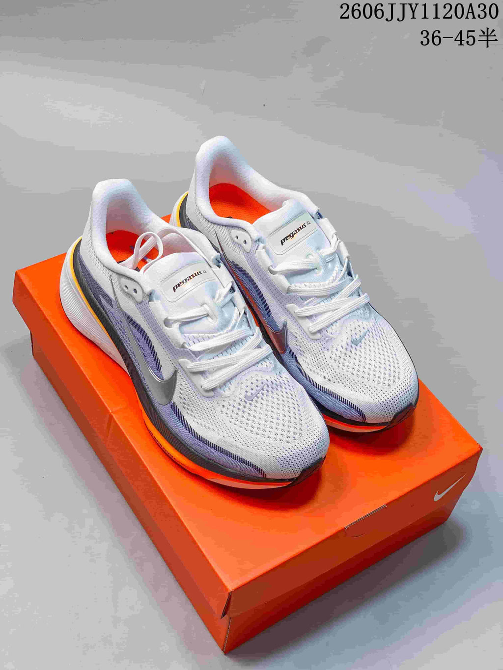 Pair of white and light purple Nike Pegasus 42 running shoes with silver and orange details, shown on an orange shoe box.