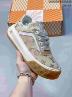 Angled close-up of a beige monogram-patterned low-top sneaker with white laces, white side trim, and a gum-colored sole.