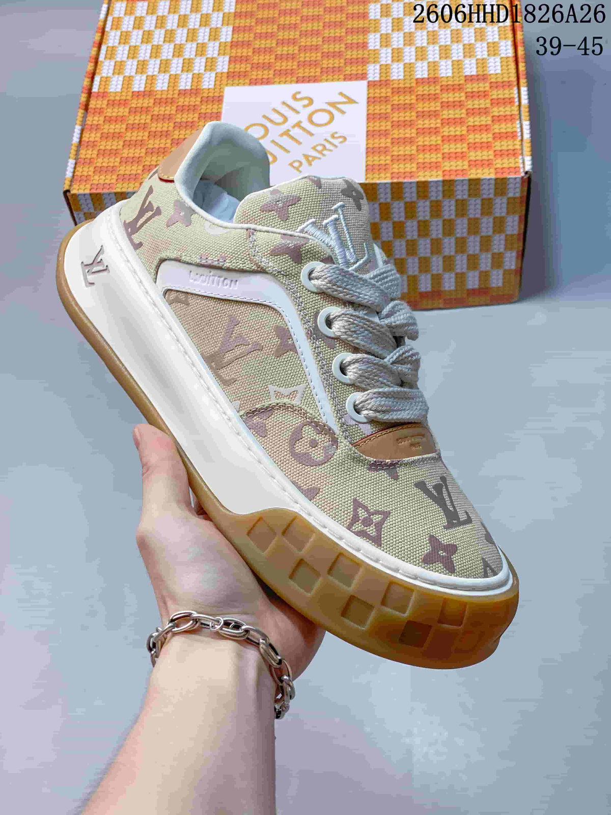 Angled close-up of a beige monogram-patterned low-top sneaker with white laces, white side trim, and a gum-colored sole.