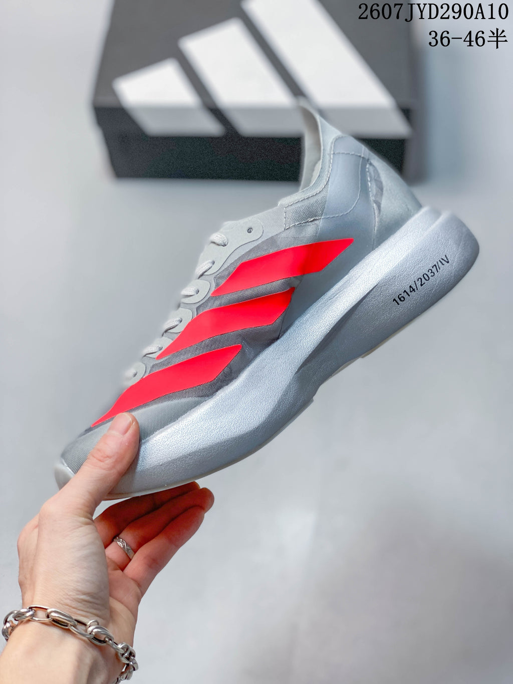 Side profile showing the gray upper, bright red three-stripe detailing, and raised light-colored sole.