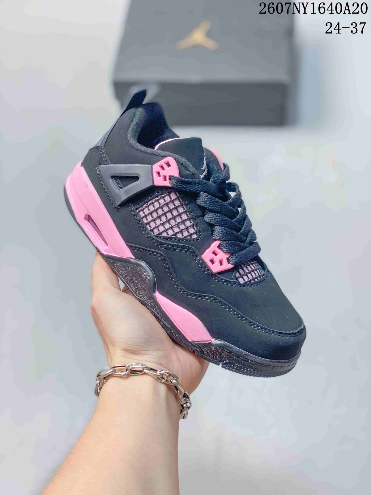 Three-quarter side view of the black and pink low-top sneaker with mesh panel and patterned outsole.