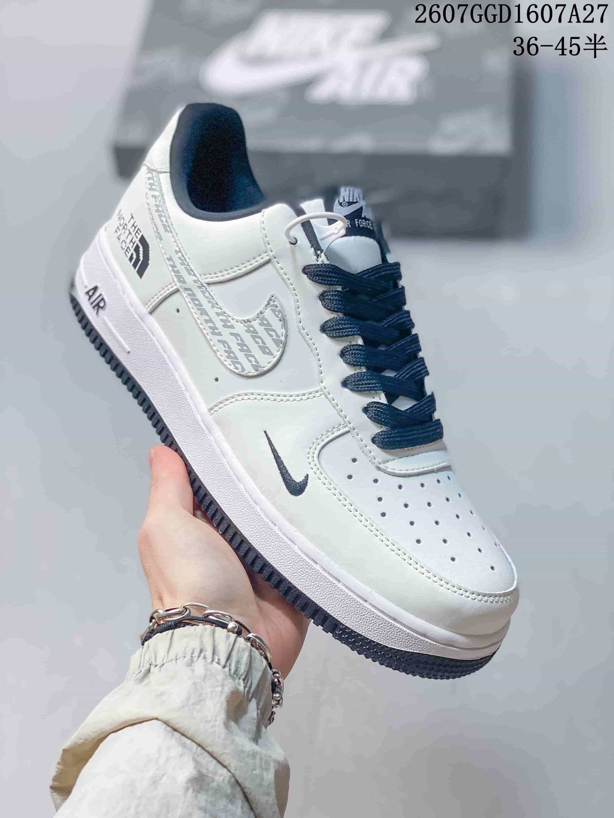 Angled side view showing the white upper, dark laces, layered side graphics, heel branding, and dark outsole.