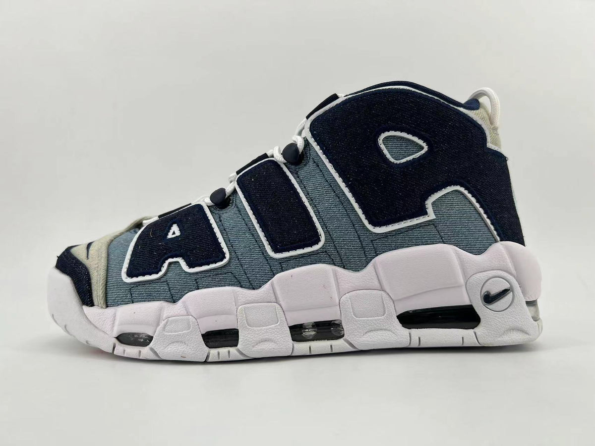 Side view of a Nike Air More Uptempo sneaker in blue-gray, dark navy, and off-white with oversized AIR lettering and a chunky sole.