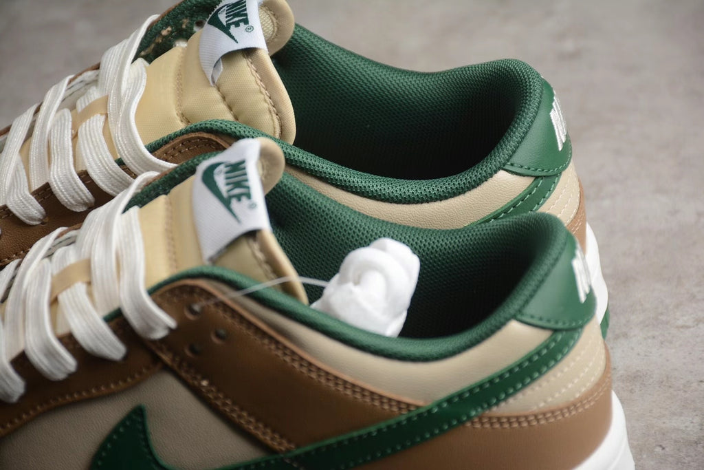 Close-up of the brown, cream, and green Nike SB sneakers showing the padded green collar, cream panels, white laces, and tongue branding.