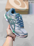 Angled front-side view of the ASICS Gel-Cumulus 16 sneaker showing the mesh upper, blue and green accents, and model text on the side.
