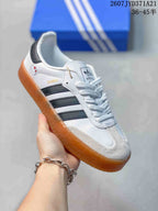 Angled side view showing the Samba branding, black stripes, white upper, and gum sole.