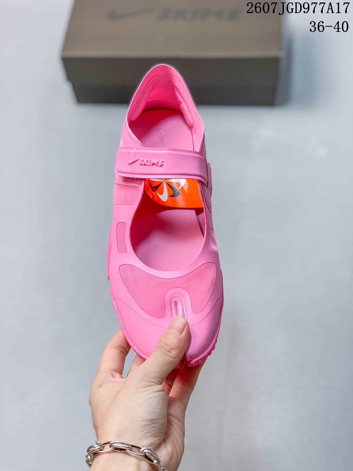 Top view of one pink sneaker showing the split-toe opening, adjustable strap and branded details.