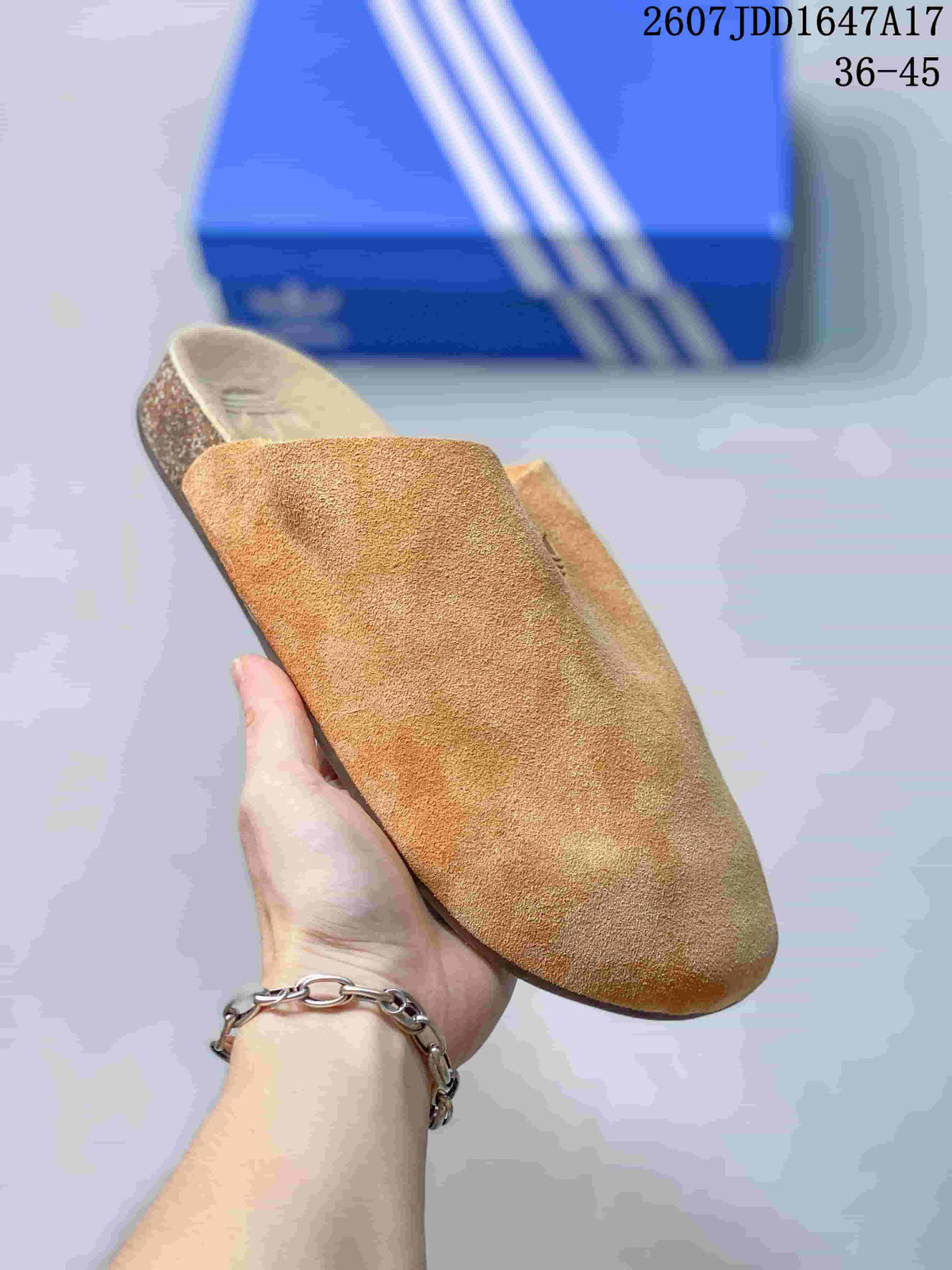 Angled view of a tan closed-toe mule showing the upper texture, open heel, footbed, and dark textured outsole.