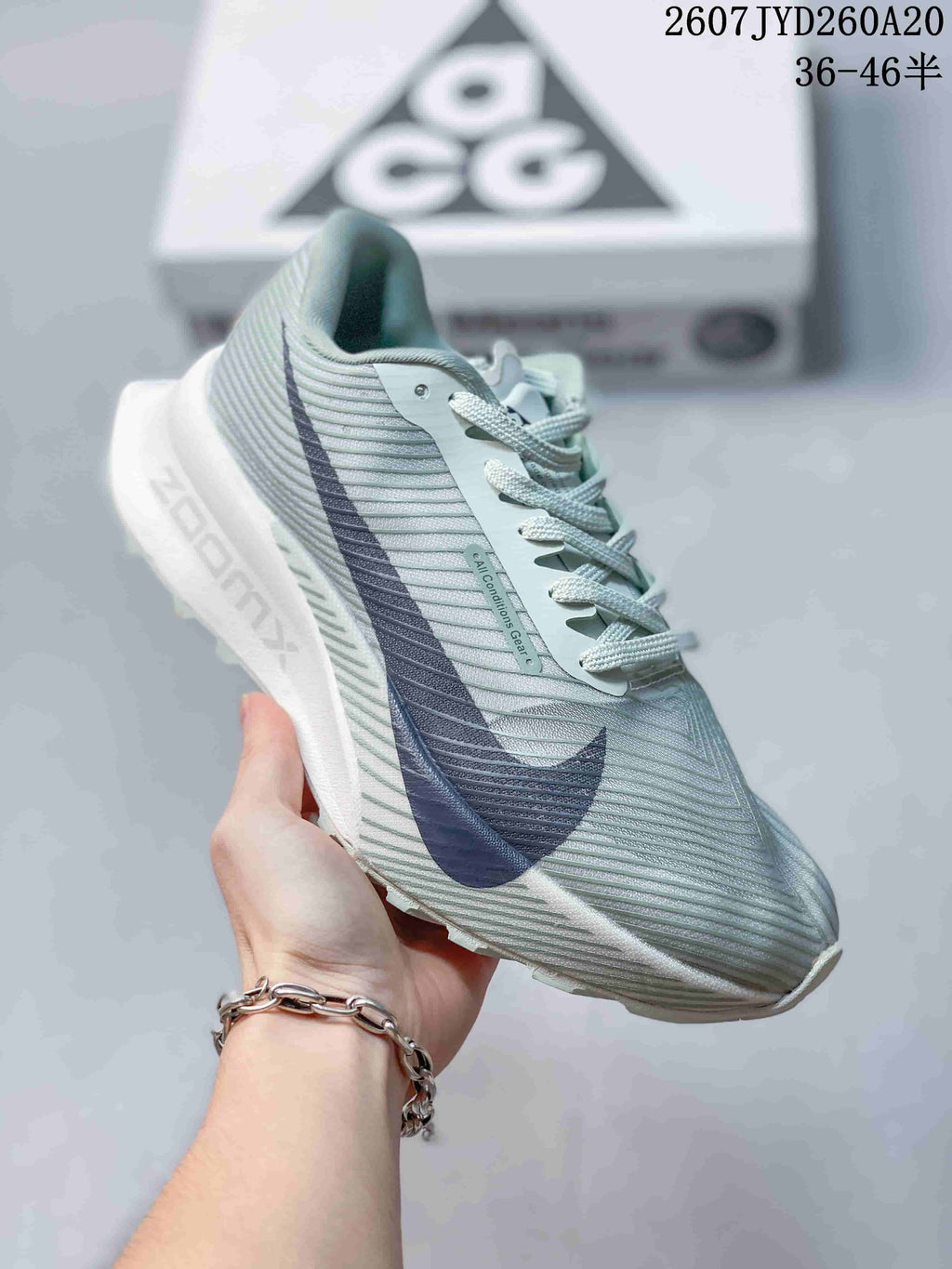 Side profile of the Nike ACG sneaker showing the textured pale green upper, navy Swoosh, white midsole, and trail-style outsole.