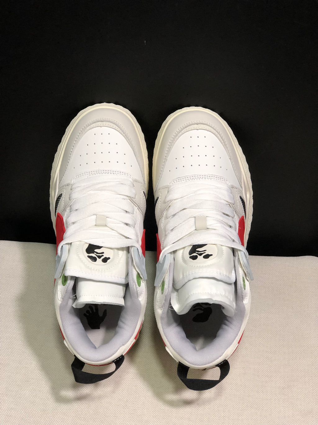 Top-down view showing white laces, perforated toe boxes, green eyelet accents, and black tongue graphics.