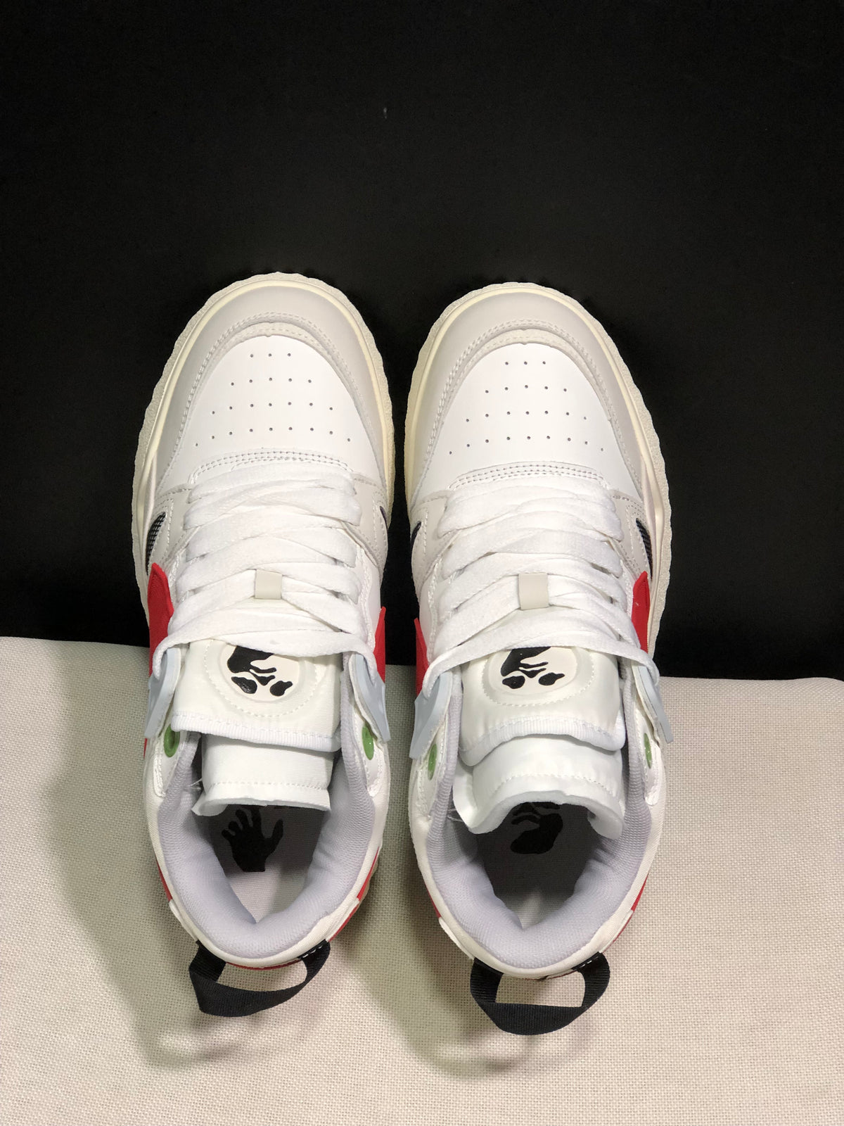 Top-down view showing white laces, perforated toe boxes, green eyelet accents, and black tongue graphics.