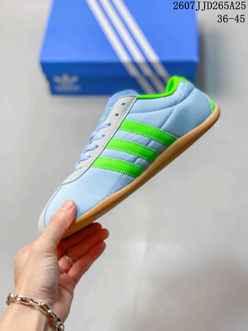 Side view highlighting the light blue upper, bright green three stripes and low-profile sole.