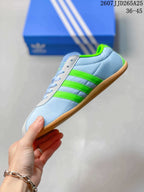 Side view highlighting the light blue upper, bright green three stripes and low-profile sole.