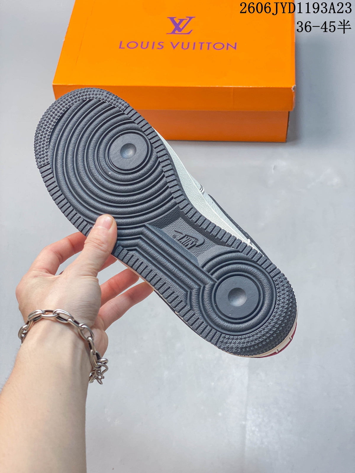 Underside of a sneaker showing a dark outsole with circular tread patterns